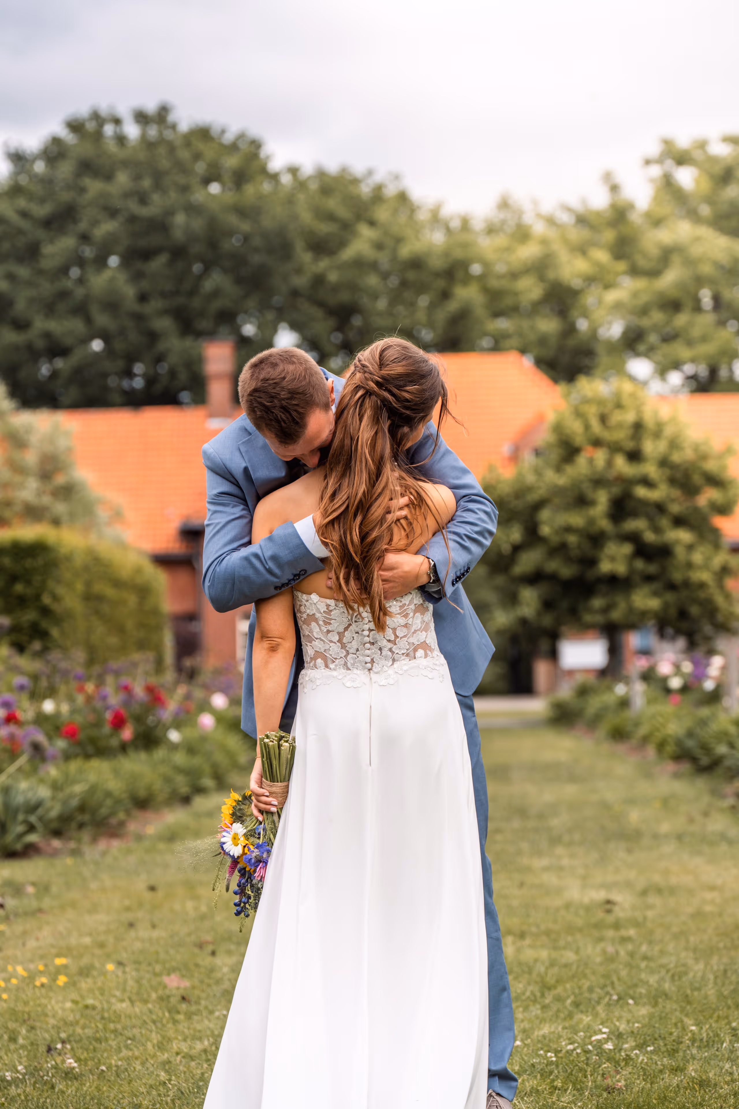 Bruidspaar omhelst elkaar; de bruid houdt haar bruidsboeket vast.